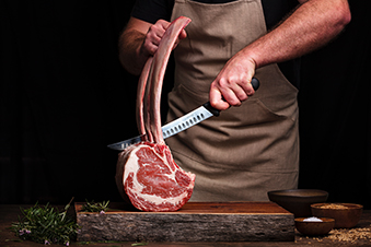 Photo d'un boucher coupant un morceau de viande.