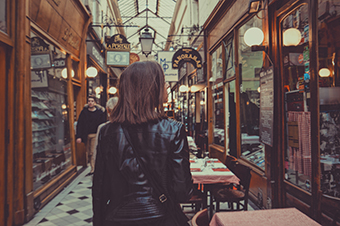 Photo d'une femme de dos se promenant dans une galerie couverte.